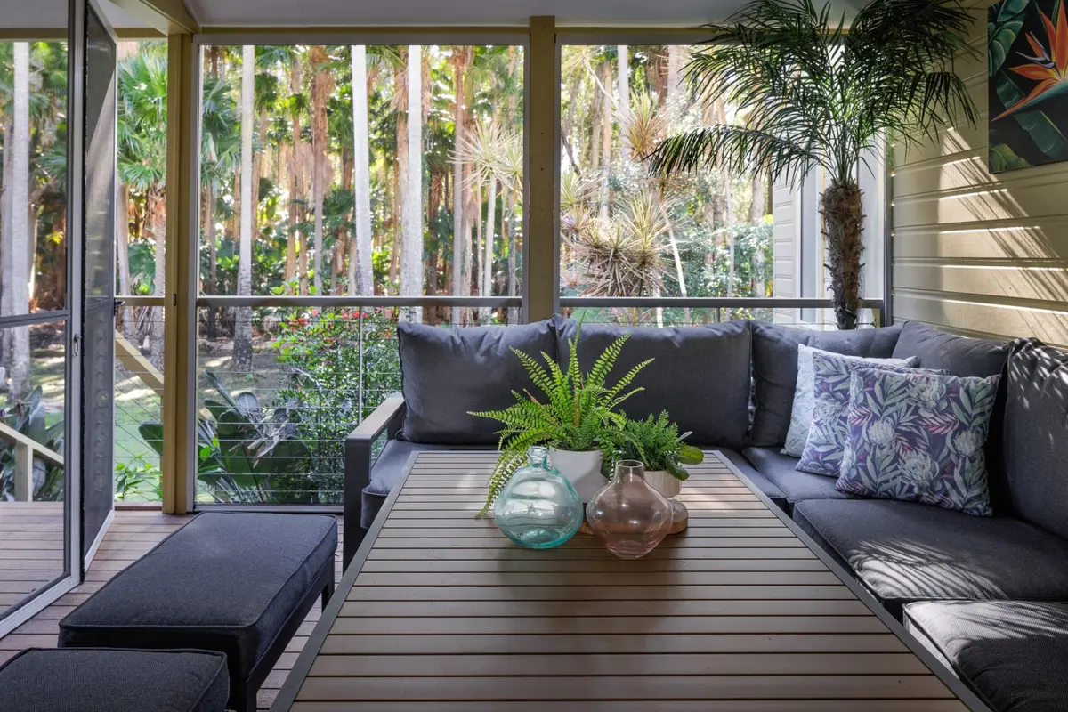 Screened outdoor lounge surrounded by tropical gardens at Blueys Retreat